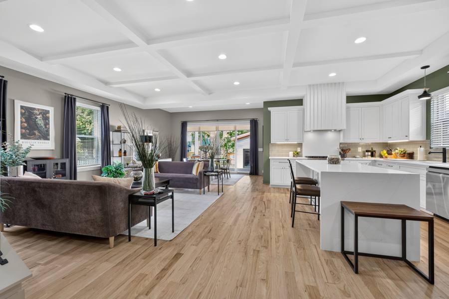 Open kitchen and living area with sage green accent walls and white cabinets