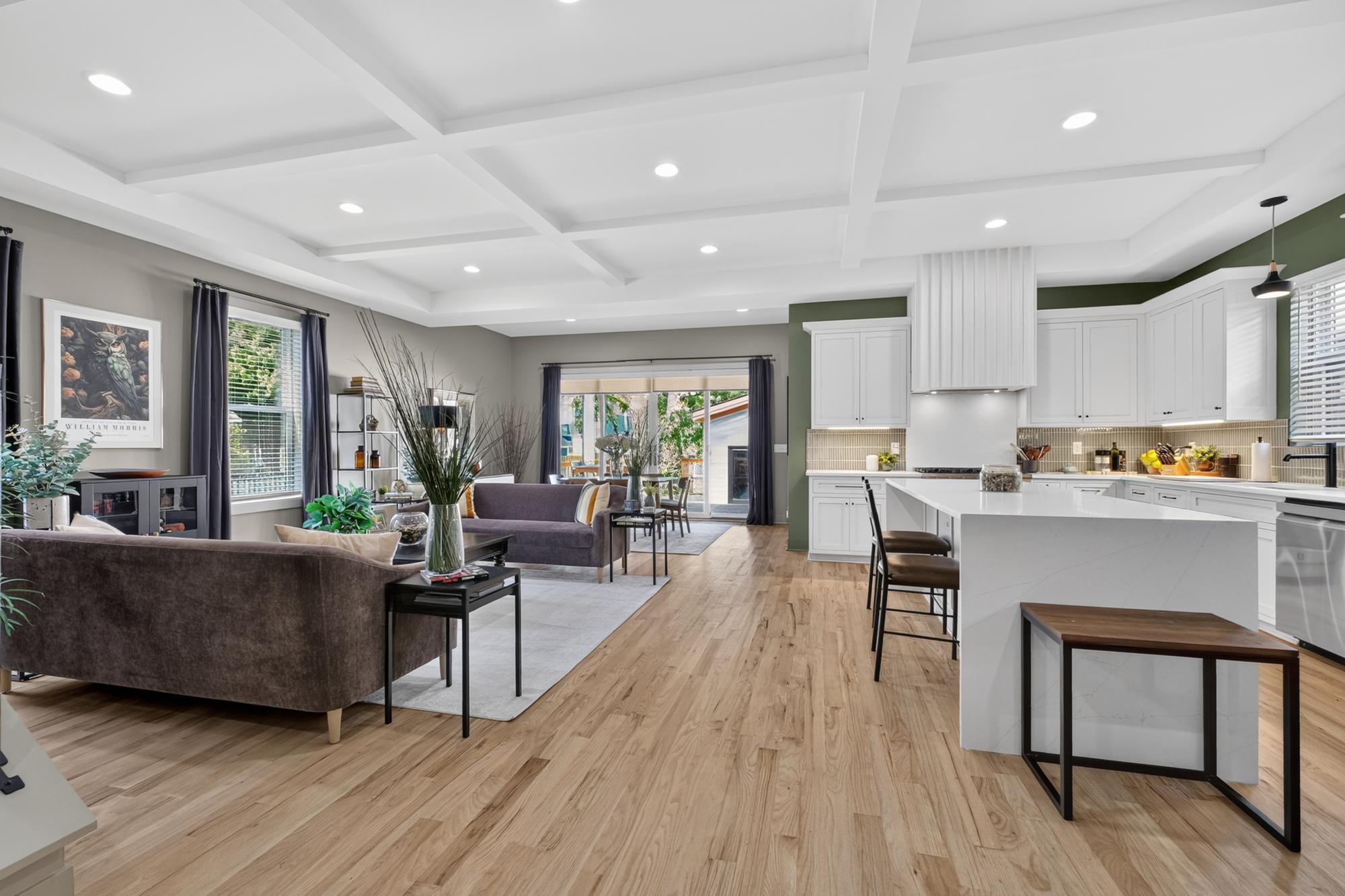 Open kitchen and living area with sage green accent walls and white cabinets