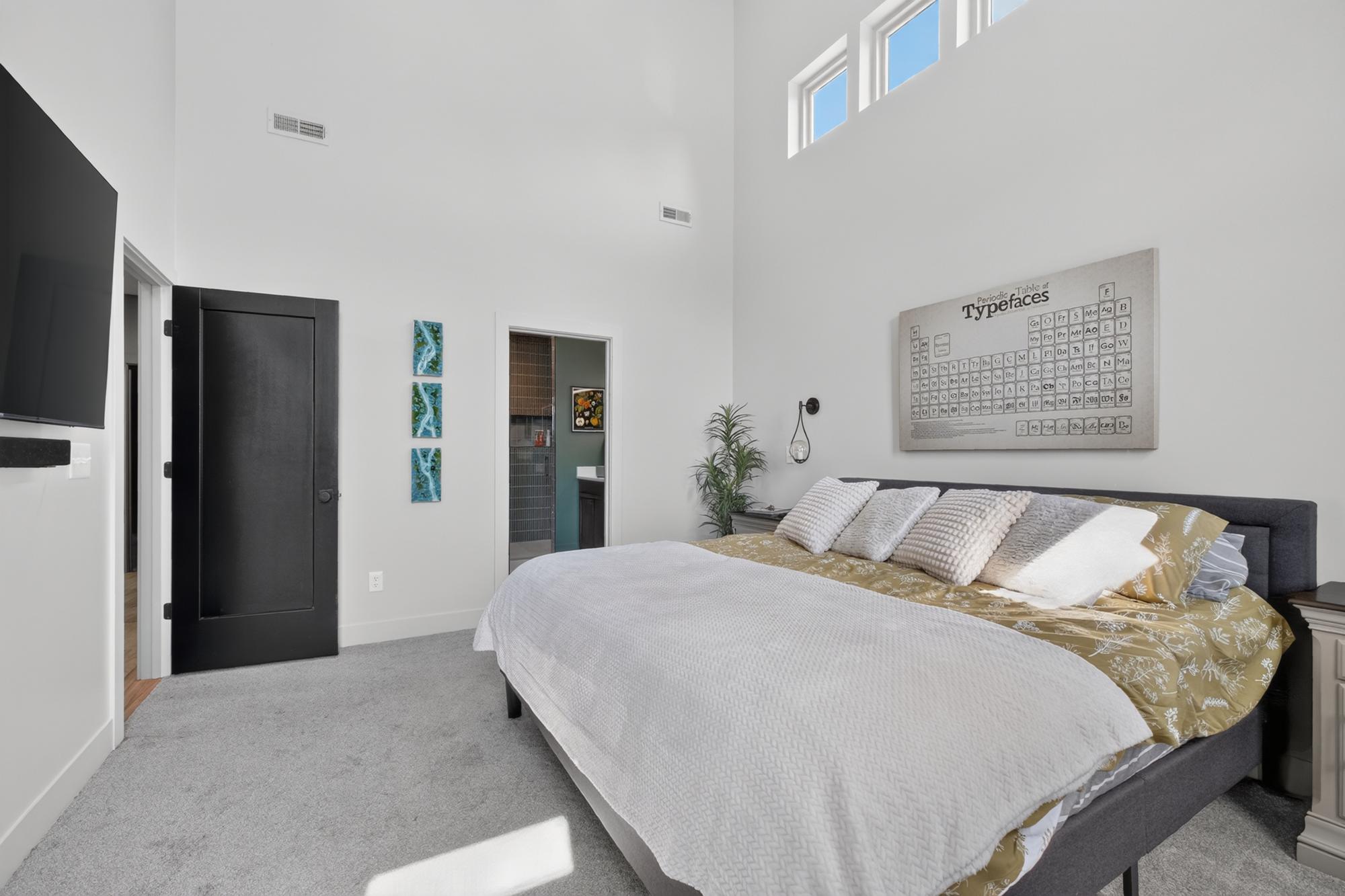 Primary bedroom with light gray walls and a tall window