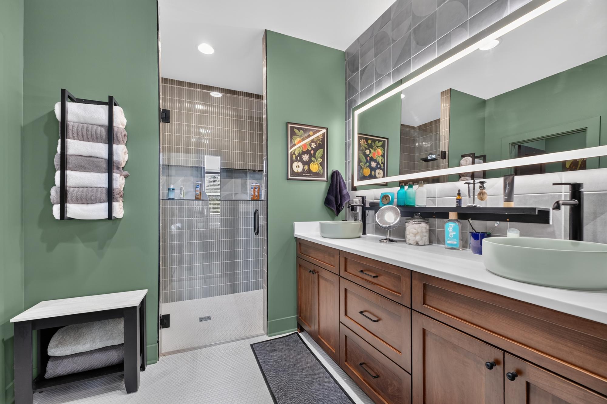 Primary bathroom with sage green walls, wood vanity and black fixtures