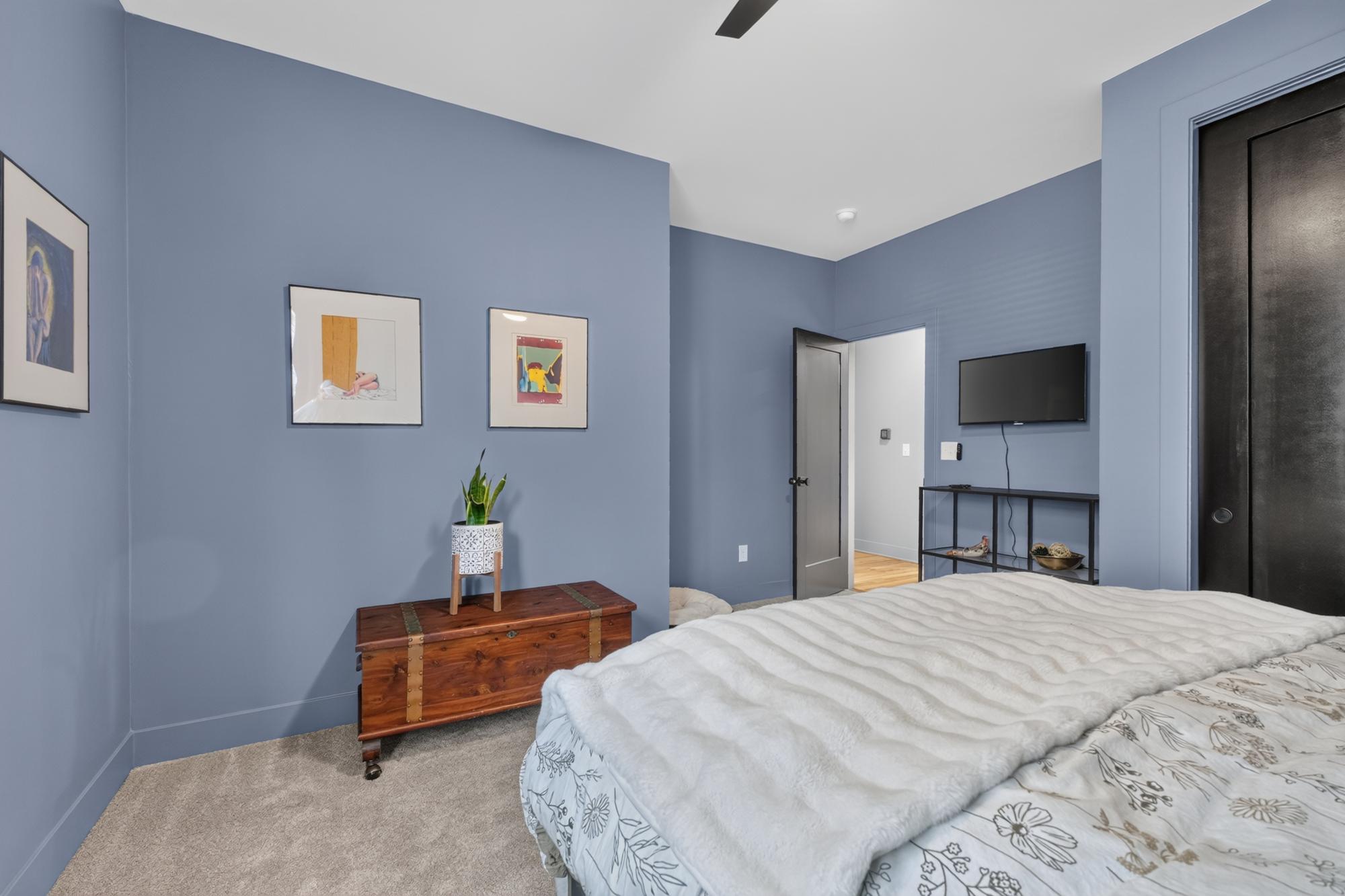 Bedroom with slate blue walls, framed art and a wood chest