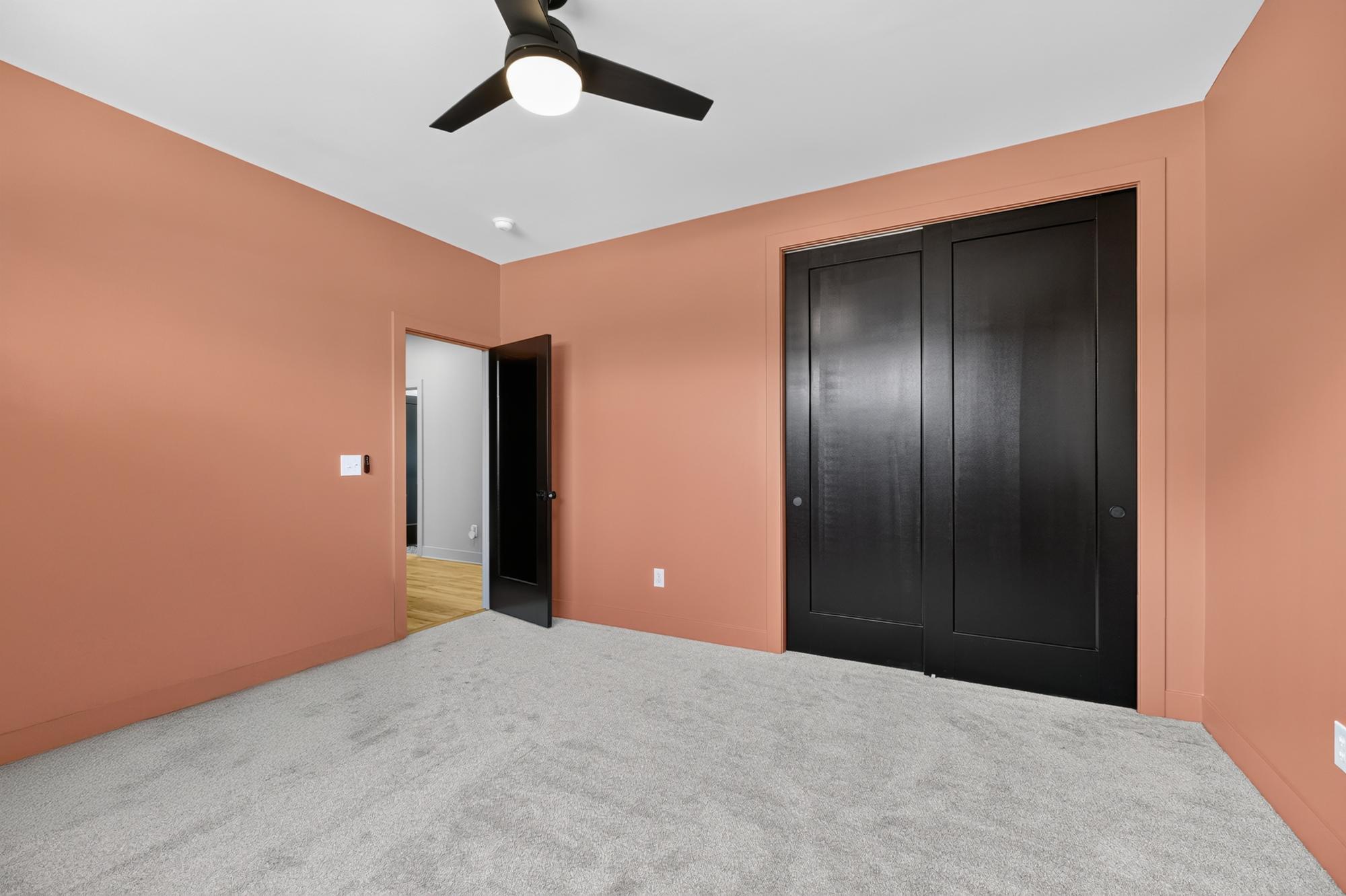 Bedroom with terracotta walls and black double closet doors