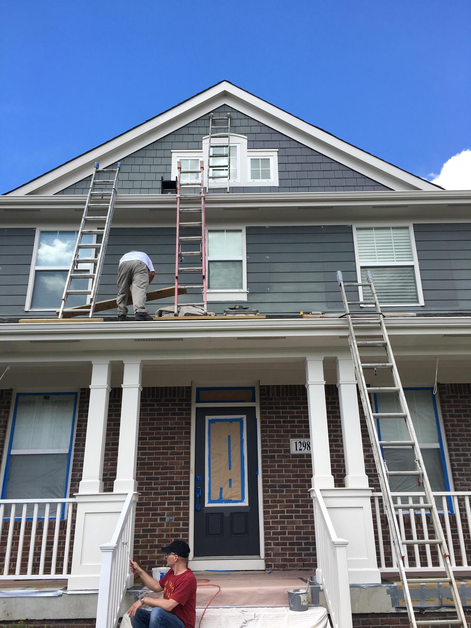 Ladders against a Craftsman-style home with white porch columns